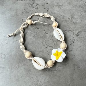 A frangipani and seashells food bracelet on a gray surface